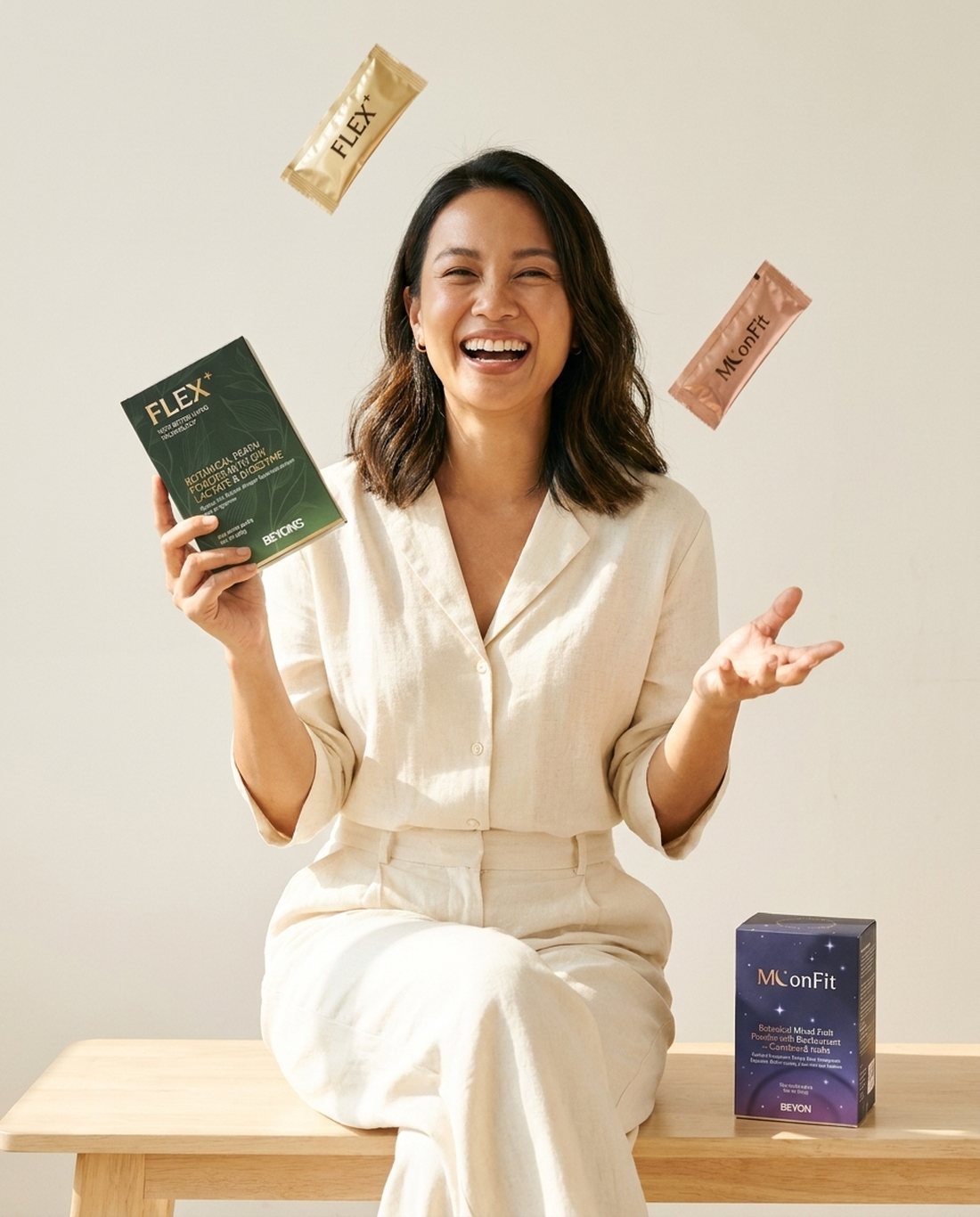A woman laughing joyfully while holding the BEYON FLEX+ box, with FLEX+ and MoonFit sachets in the air